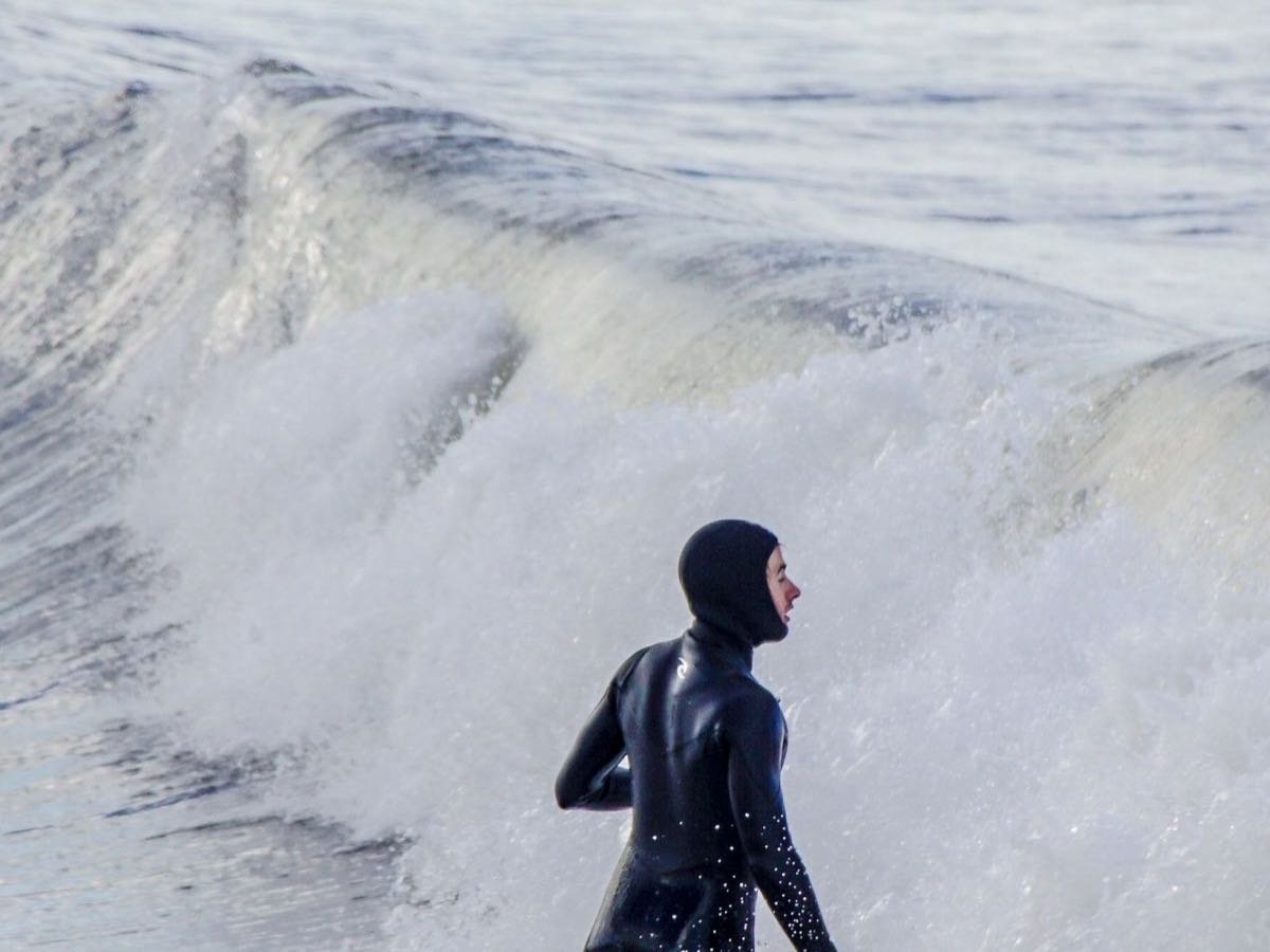 Surfer standing near breaking waves