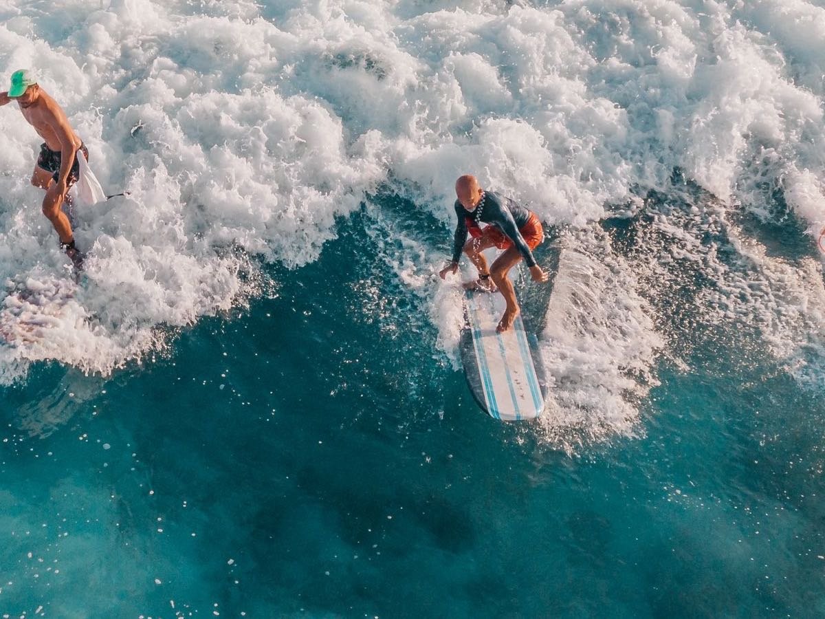 Surfers riding a wave from above